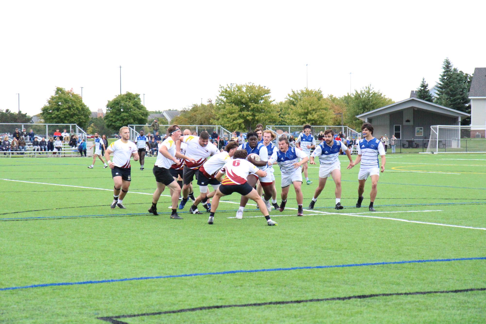 mens rugby player holding the ball running into the opposing team braced for impact. teammates running behind him to support